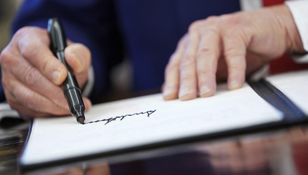 President Donald Trump signs an executive order in the Oval Office of the White House, April 9, 2025, in Washington. (Pool via AP)